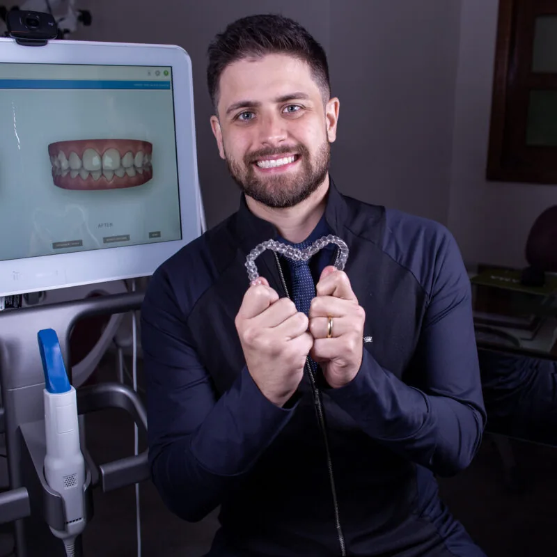 Dr. Marcos segurando alinhadores Invisalign em formato de coração
